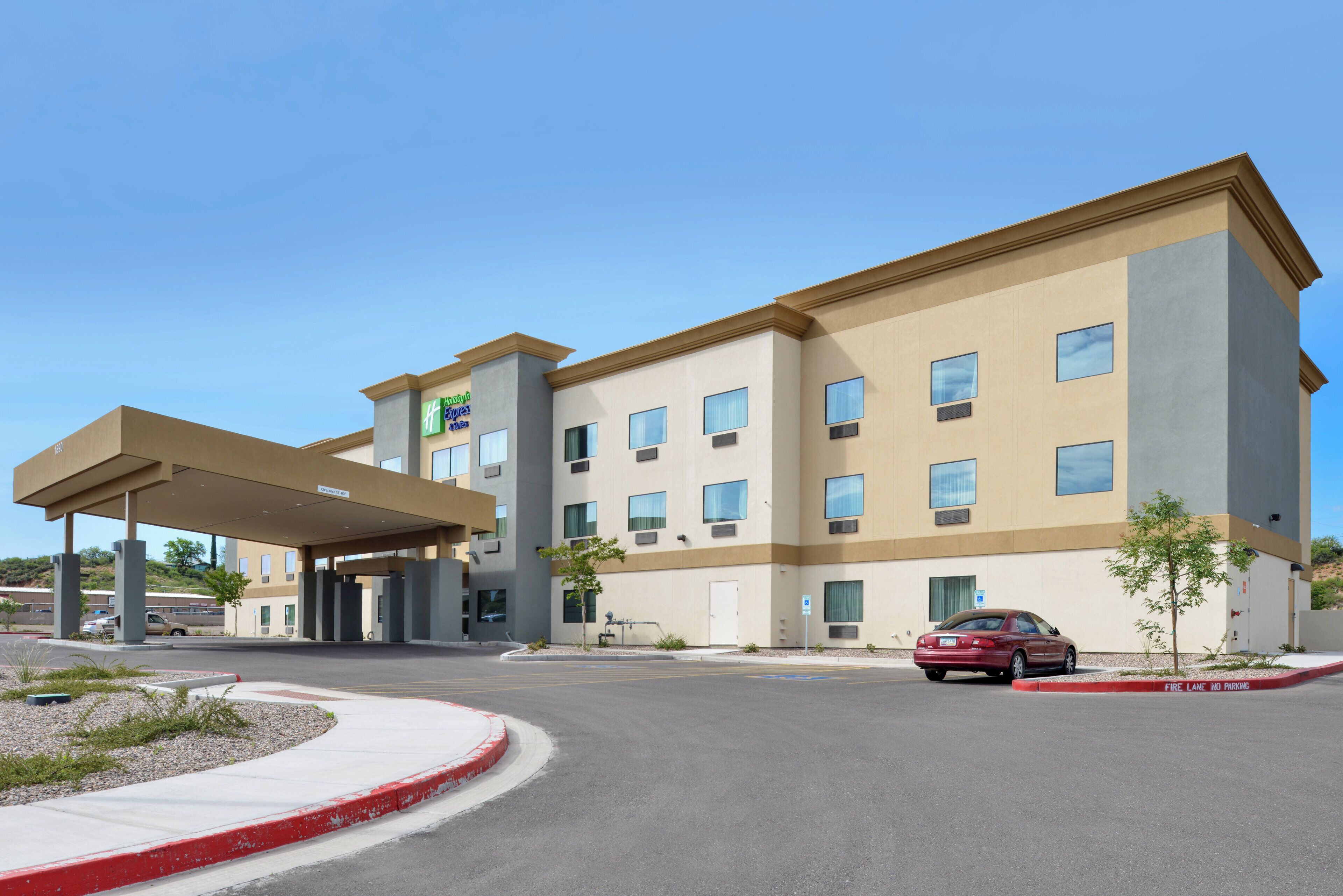 A hotel with a covered entrance, multiple windows, and a car parked in front.