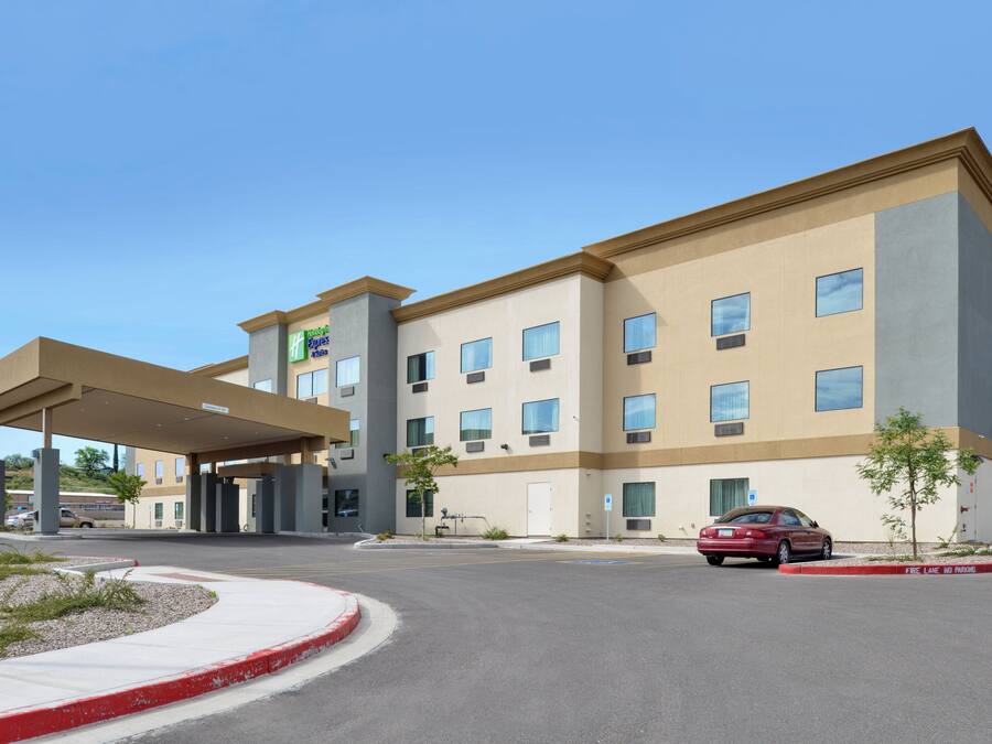 A hotel with a covered entrance, multiple windows, and a car parked in front.