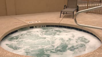Relax in the hot tub surrounded by a tiled border, complete with a comfortable chair and handrail.