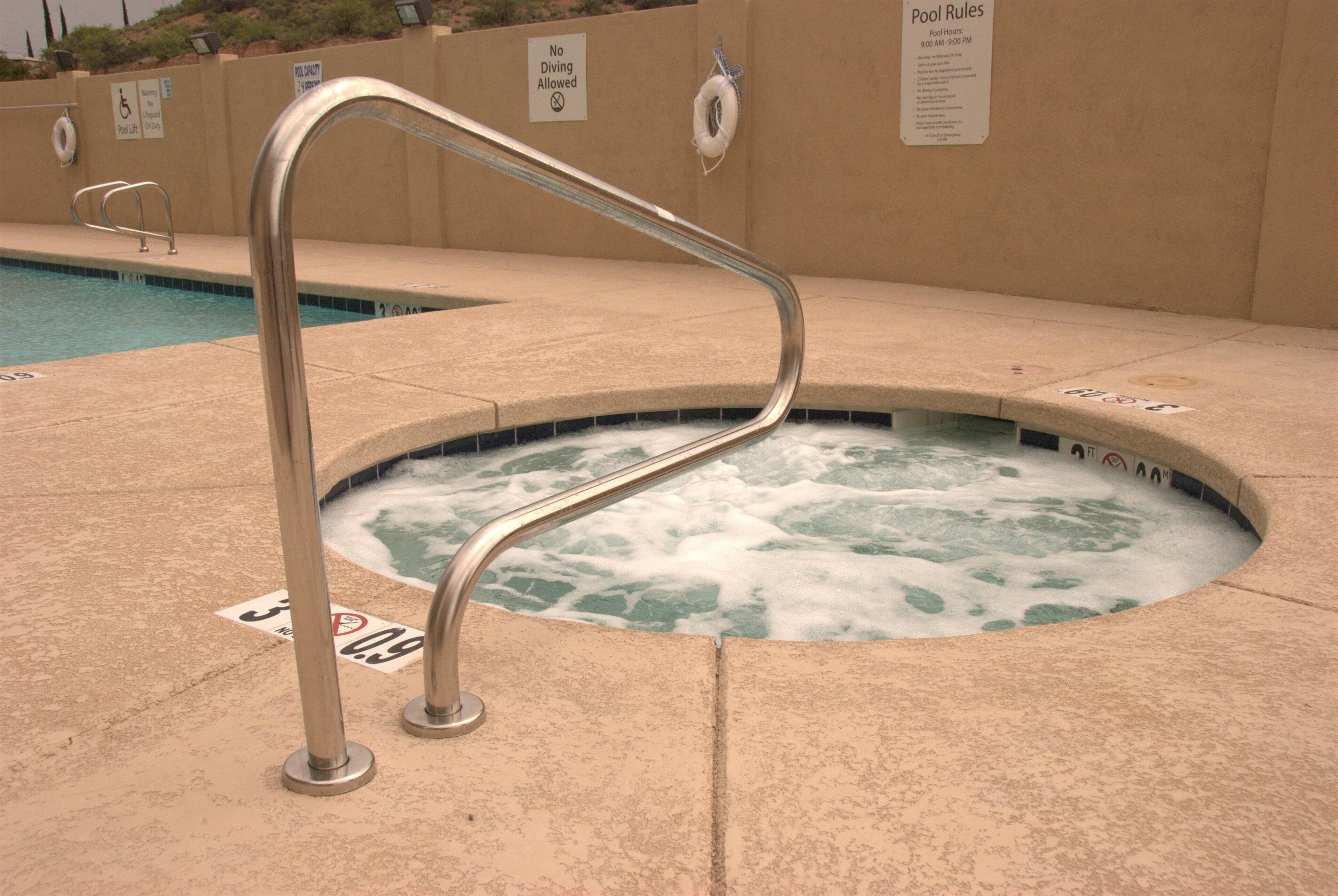 A hot tub with a metal ladder, surrounded by a tiled deck.