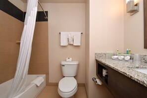 Un baño moderno con bañera, inodoro y tocador con encimera.