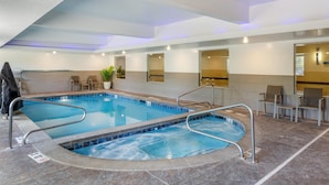 Une piscine avec un bord carrelé, un espace avec des chaises et une plante en pot.