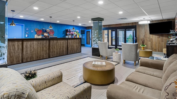 Un hall d’entrée moderne doté d’un comptoir de réception, de sièges confortables, d’un téléviseur à écran plat et d’une grande fenêtre.