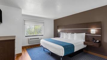 Une chambre d’hôtel avec un lit, une table de chevet avec une lampe, une fenêtre et un radiateur fixé au mur.