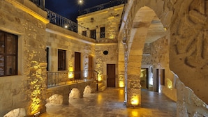 A stone interior with a central staircase, multiple windows, and a balcony with ornate railings. - Golden Cave Suites (Ürgüp)