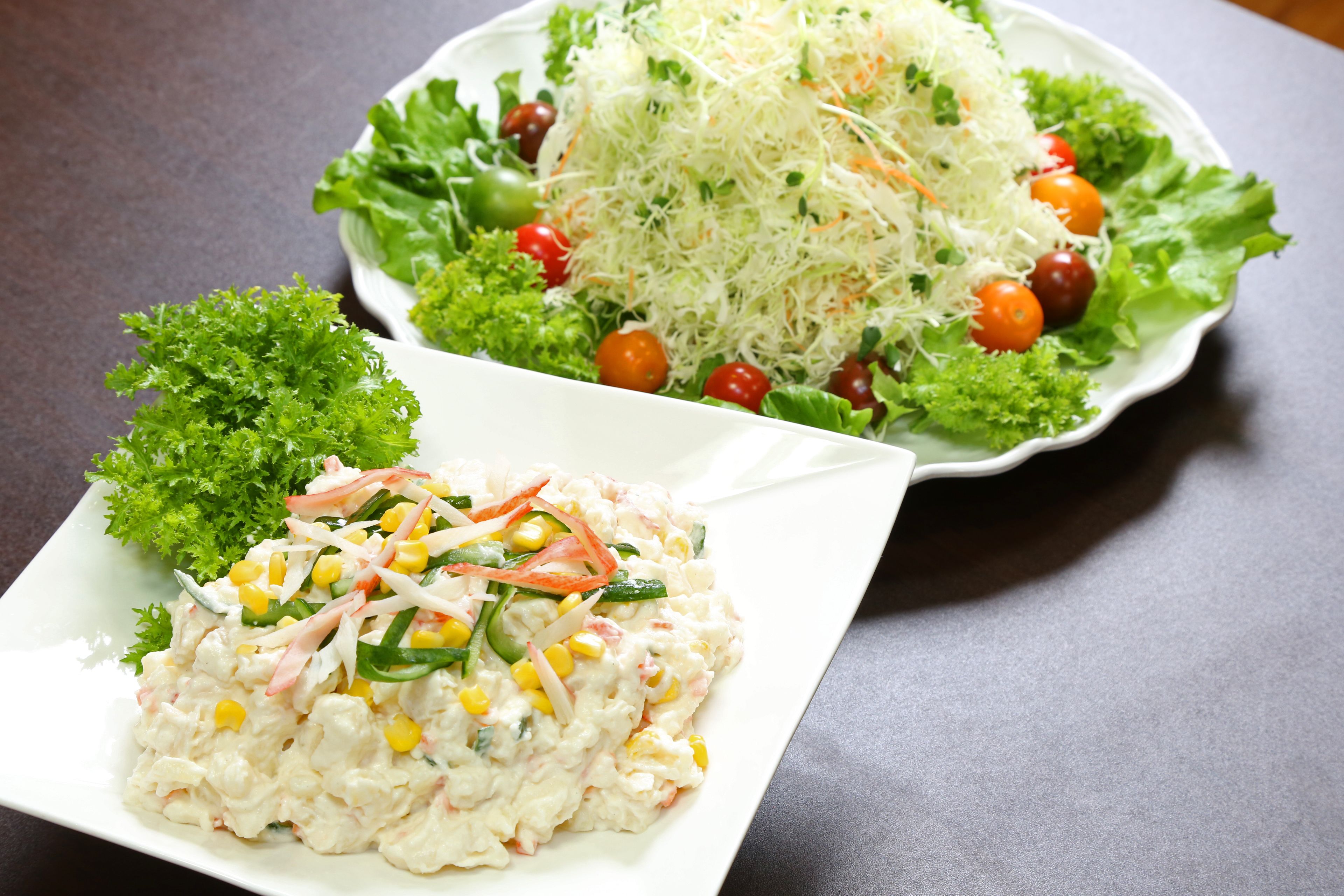 A plate of salad with shredded cheese and cherry tomatoes on a bed of lettuce.