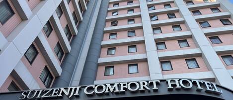The exterior of the Suizenji Comfort Hotel with a modern architectural design, featuring multiple floors and a prominent signage.