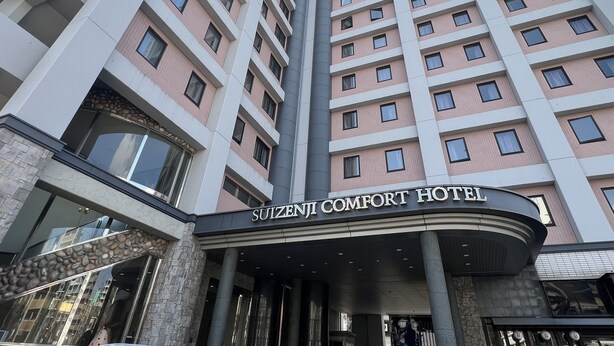 A high-rise hotel with a modern architectural design, featuring multiple balconies and a prominent entrance with a sign reading "SUIZENJI COMFORT HOTEL". - Suizenji Comfort Hotel (Kumamoto)