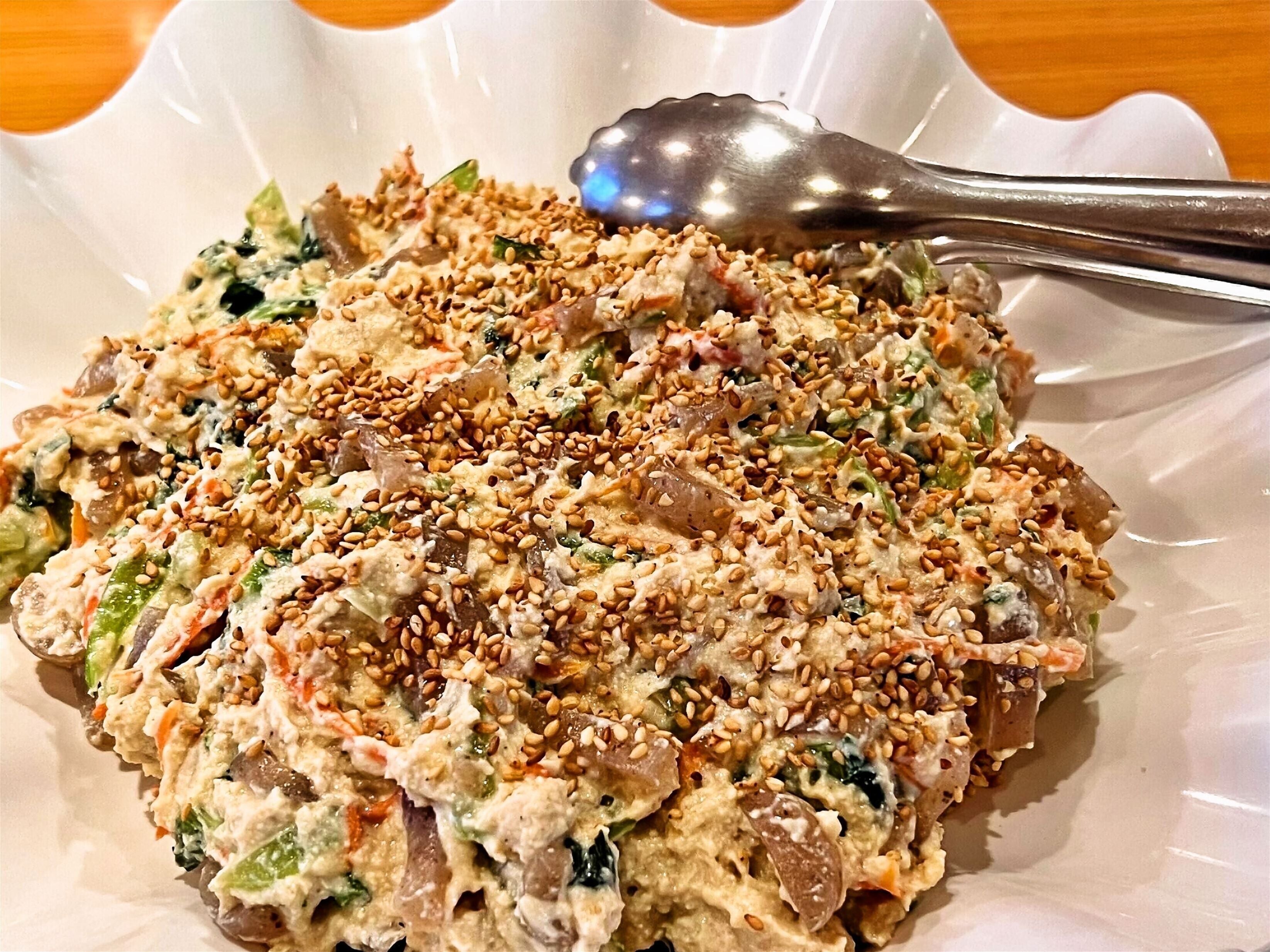 A plate of salad with various vegetables and a spoon on the side.