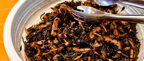 A bowl of cooked seaweed with a spoon.