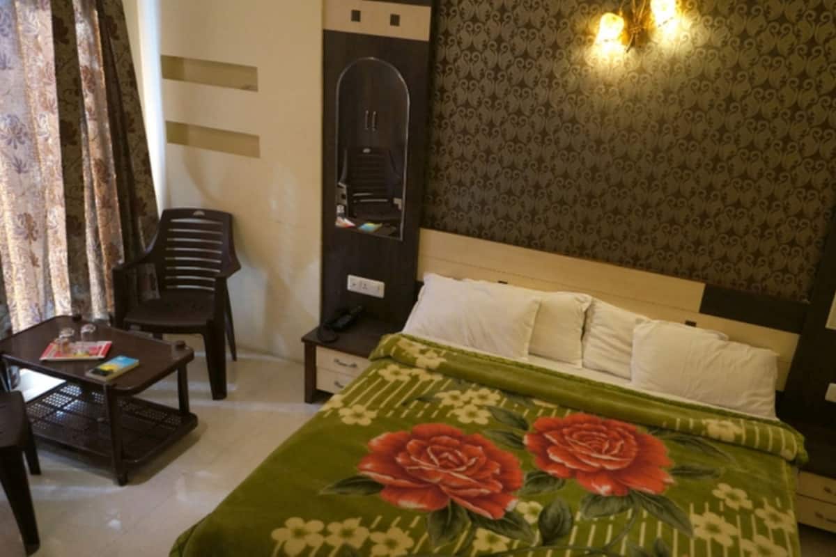 A hotel room with a bed, a desk, a chair, a wardrobe, and a mirror.