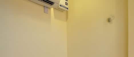 Habitación de hotel con una cama, un equipo de aire acondicionado, un teléfono y un enchufe en la pared.