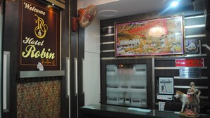 A reception area with a 'Welcome to Hotel Robin' sign, a fan, a framed picture, and a sign indicating 'Extra Bed Rs.300'. - Hotel Robin (Amritsar)