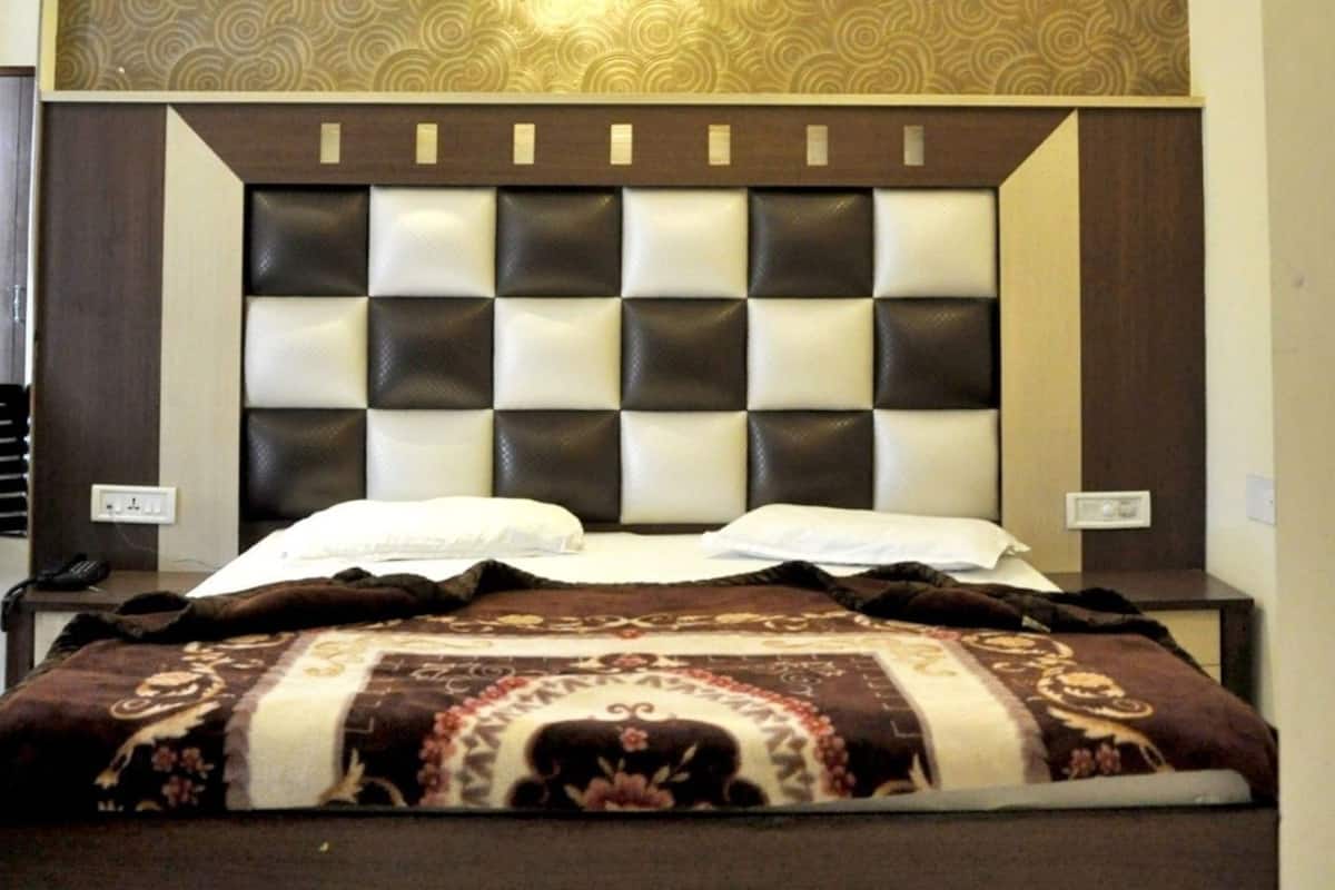 A hotel room with a bed, a ceiling fan, a wall-mounted light fixture, and a patterned wallpaper.