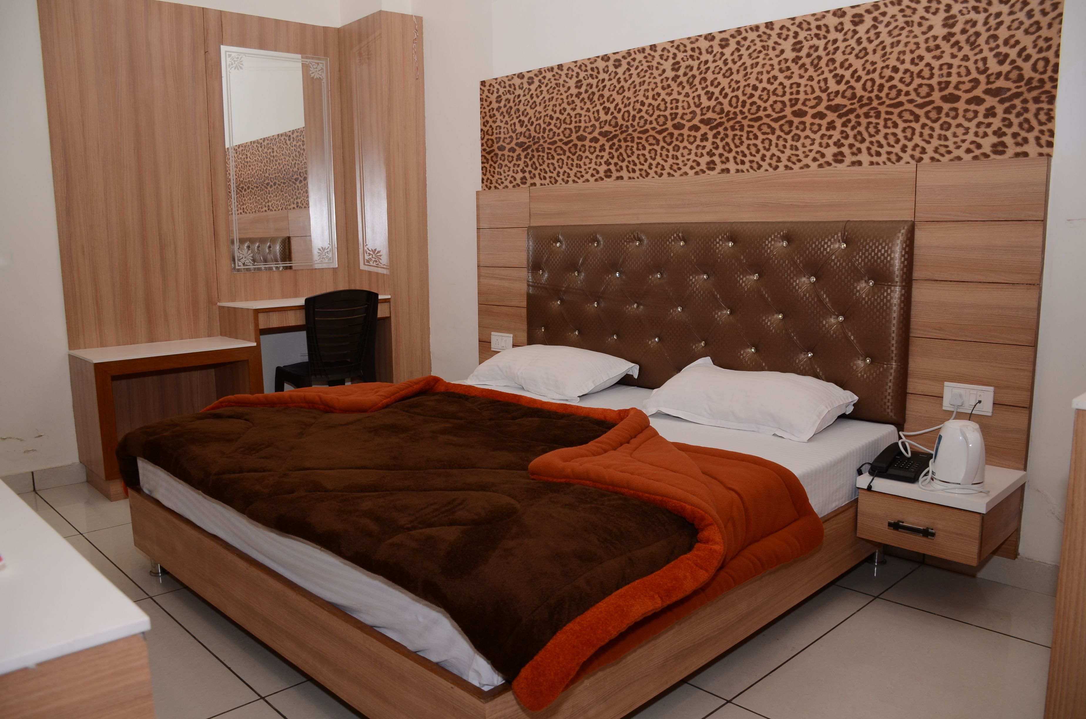 Un dormitorio con una cama grande, un escritorio, una silla y una mesita de noche con un hervidor.