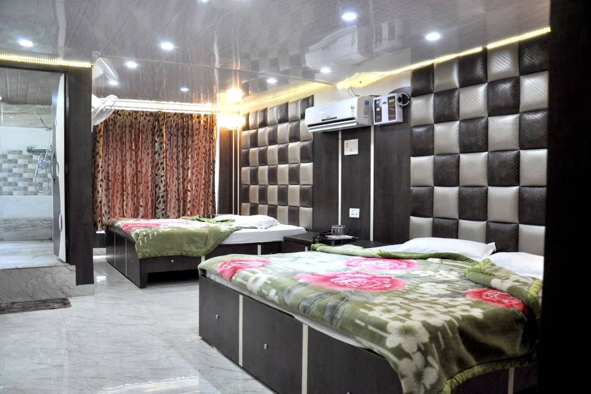A hotel room with two beds, a large mirror, an air conditioning unit, and a shower area.