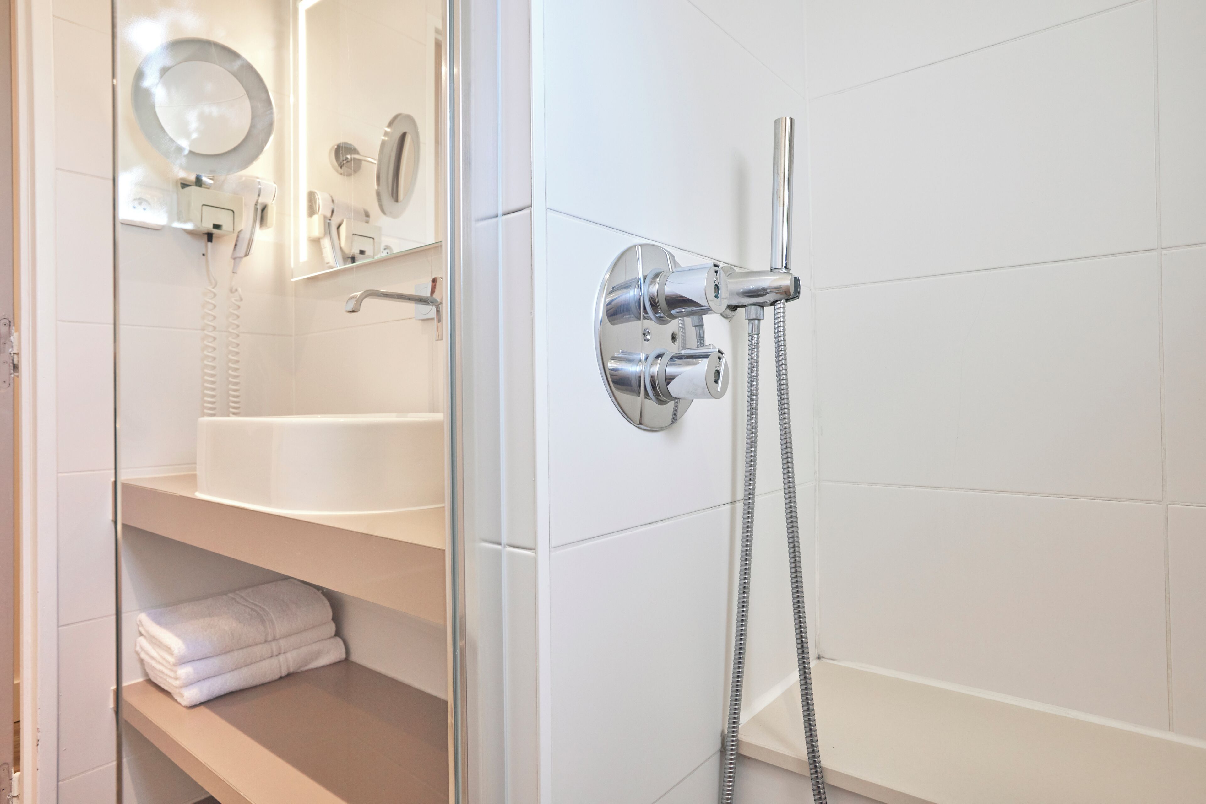 Un baño con cabina de ducha de vidrio, un lavamanos blanco y un perchero para toallas.