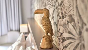 A golden toucan statue on a pedestal against a wall with a floral pattern.