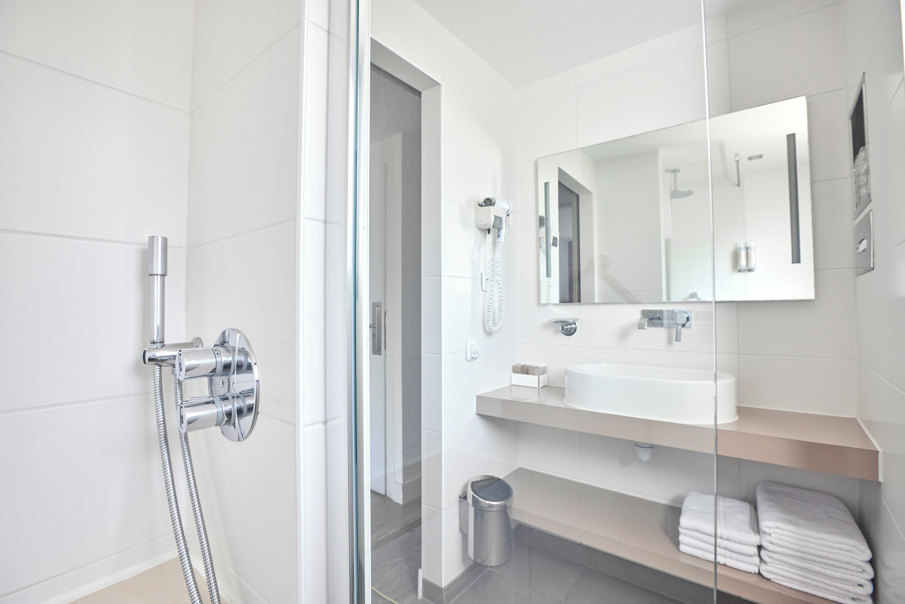 Un baño moderno con cabina de ducha de vidrio, un lavabo blanco y un espejo sobre él.