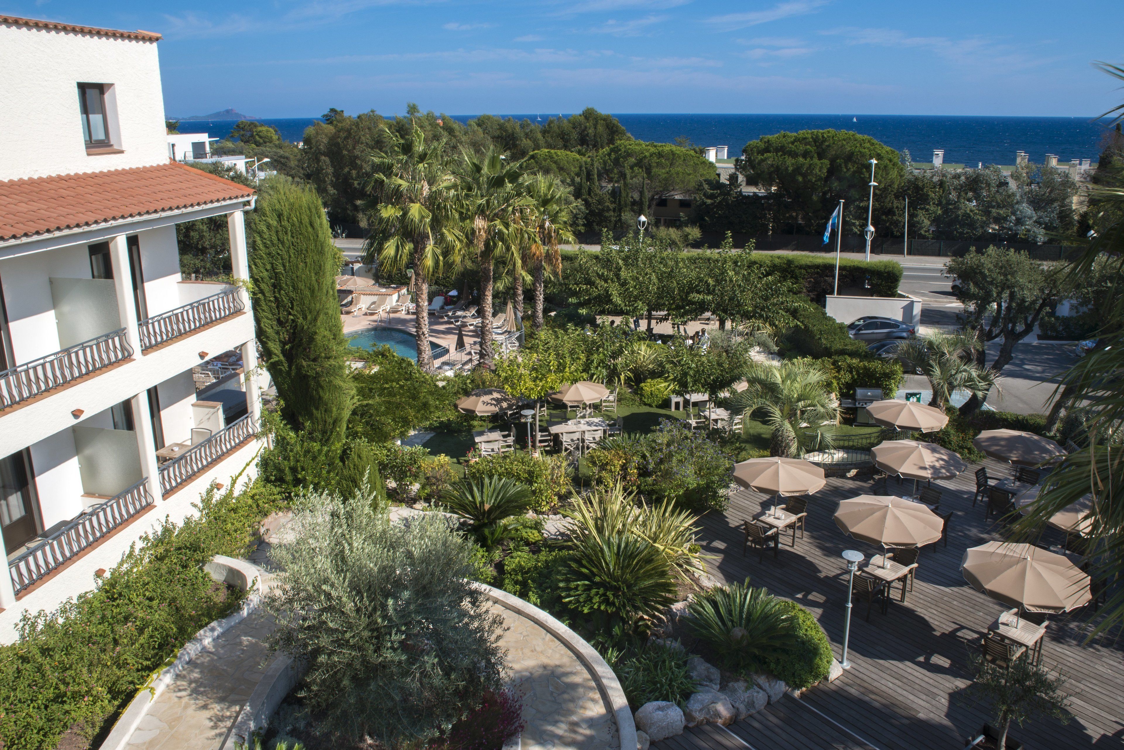 A resort with outdoor seating, a pool, and a view of the sea.