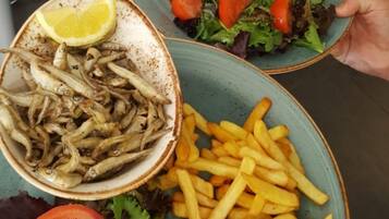 A plate with fried fish, fries, and a salad with tomatoes and lettuce.