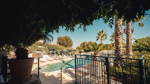 A pool area with lounge chairs and umbrellas, surrounded by palm trees and potted plants. - Van der Valk Hotel Le Catalogne Saint Aygulf (Fréjus)