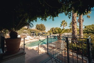 Una piscina al aire libre, sombrillas, sillones reclinables de piscina