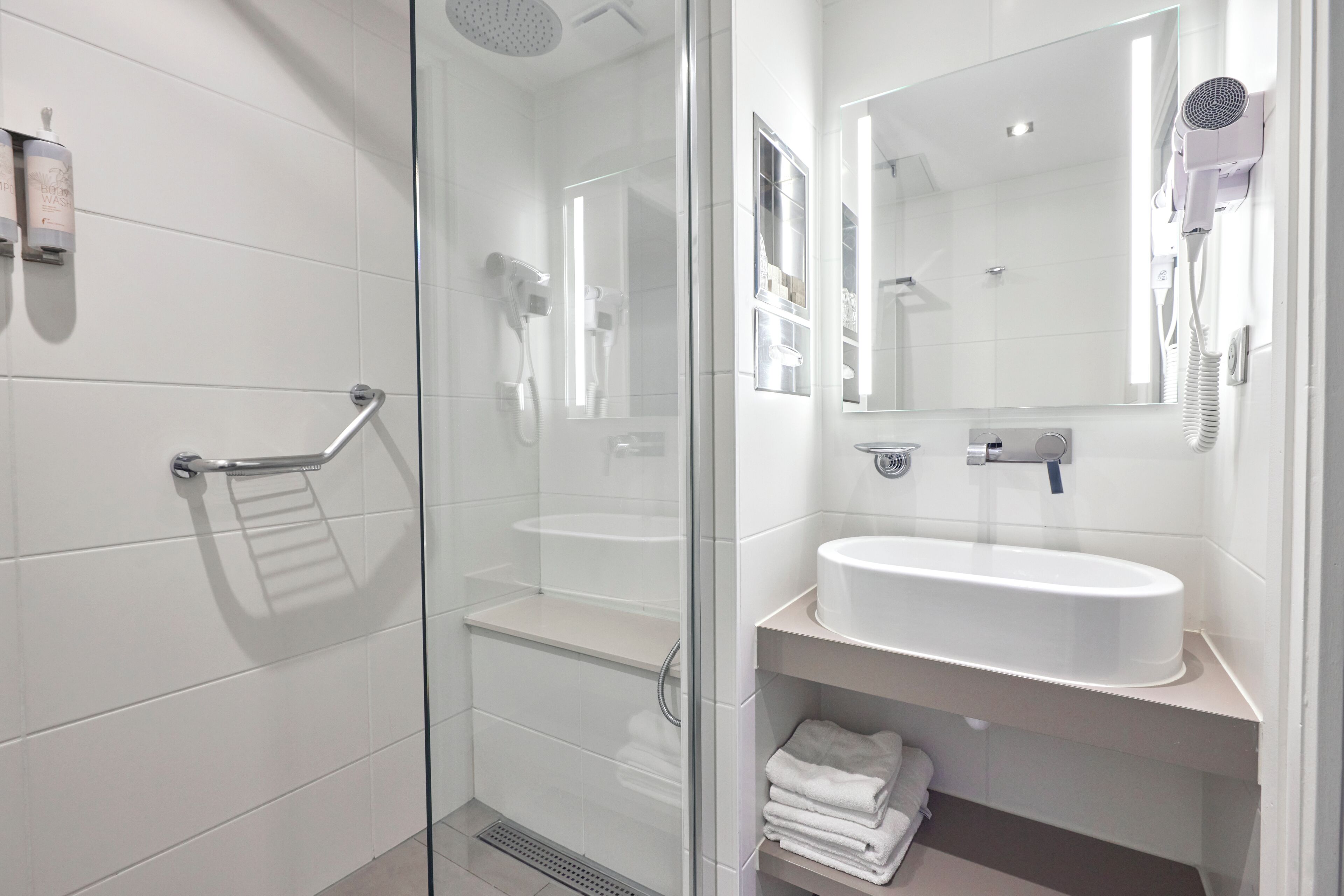 A modern bathroom with a glass shower enclosure, a white sink, and a mirror.