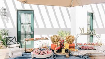 An outdoor buffet setup with various food items and a decorative sign.