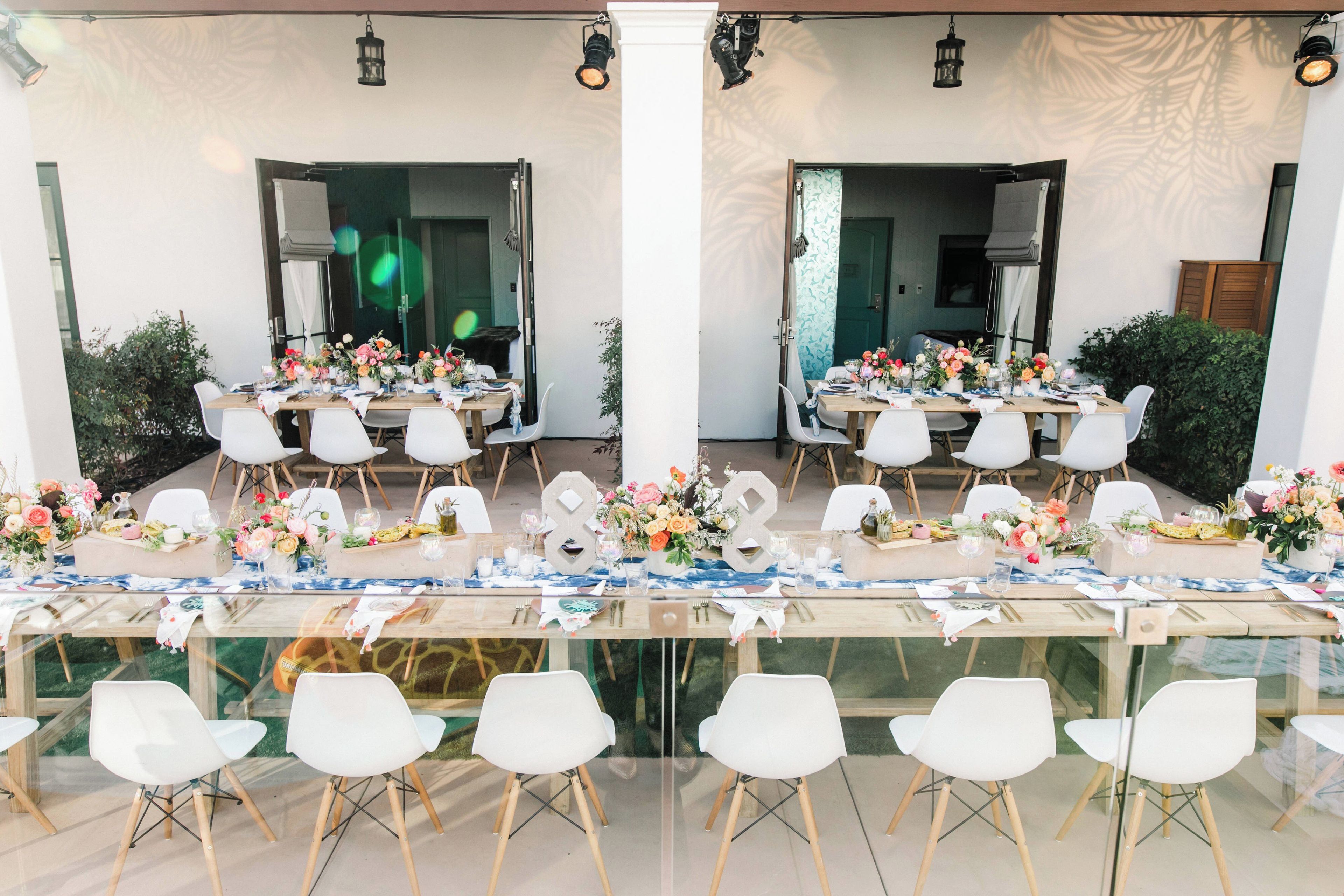 A dining area with tables set for multiple guests, chairs, and decorative centerpieces.