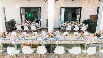 A dining area with tables set for multiple guests, chairs, and decorative centerpieces.