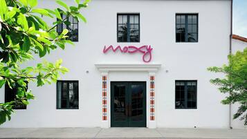 A building with a white facade, a green door, and a pink sign above the entrance.