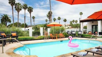 A pool area with lounge chairs, a flamingo float, and palm trees.