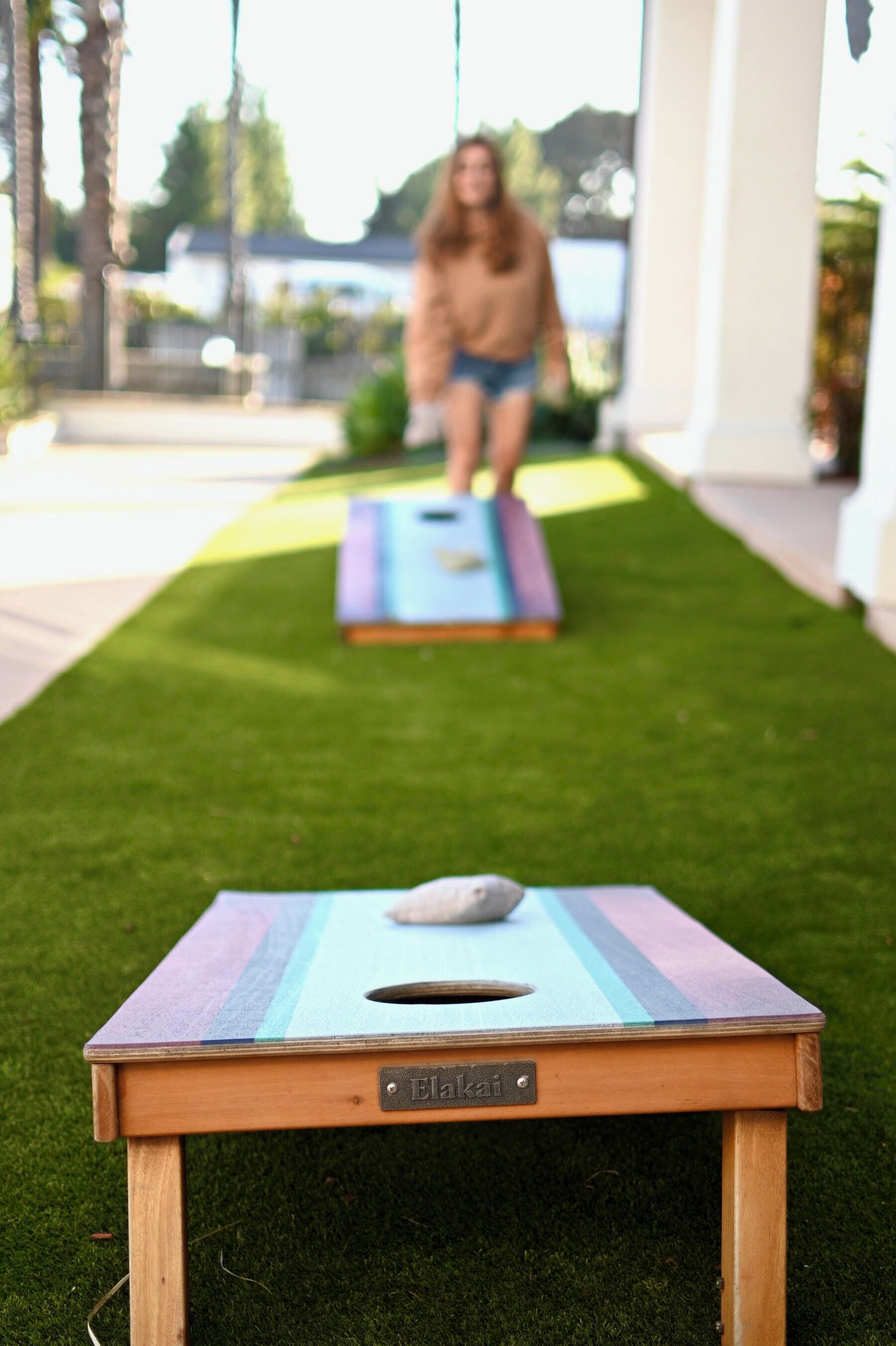 A small wooden table with a nameplate labeled 'Elakai' on a grassy lawn.