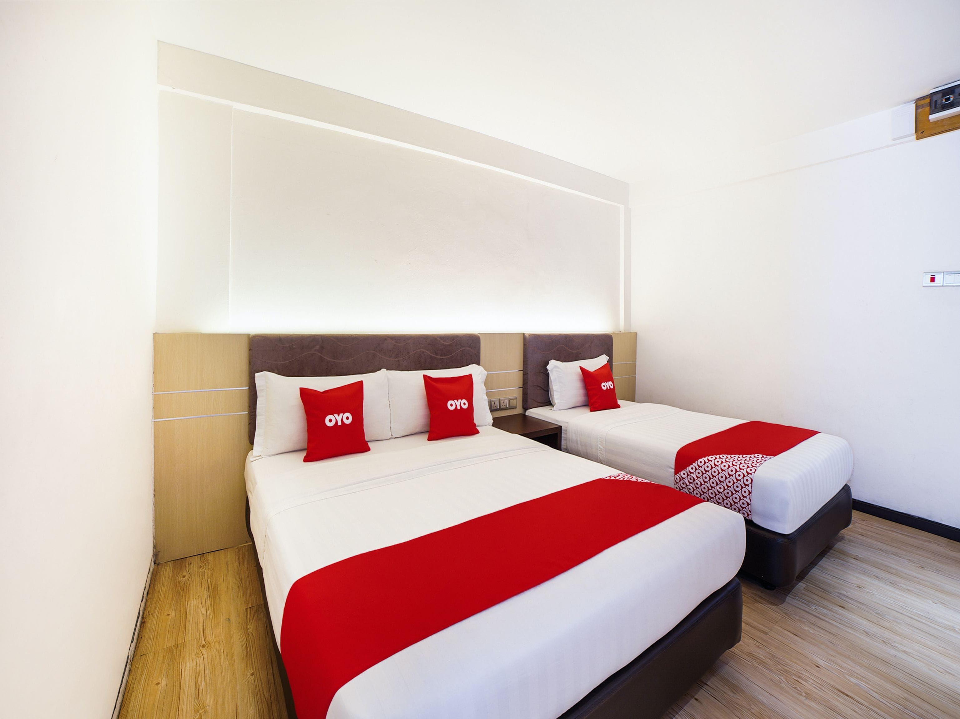 A hotel room with two beds, each with a red and white bedspread, and matching pillows.
