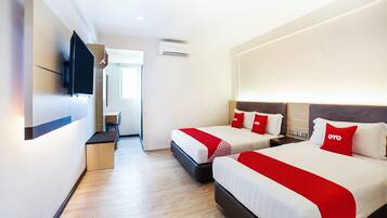 A hotel room with two beds, a desk, and a television.