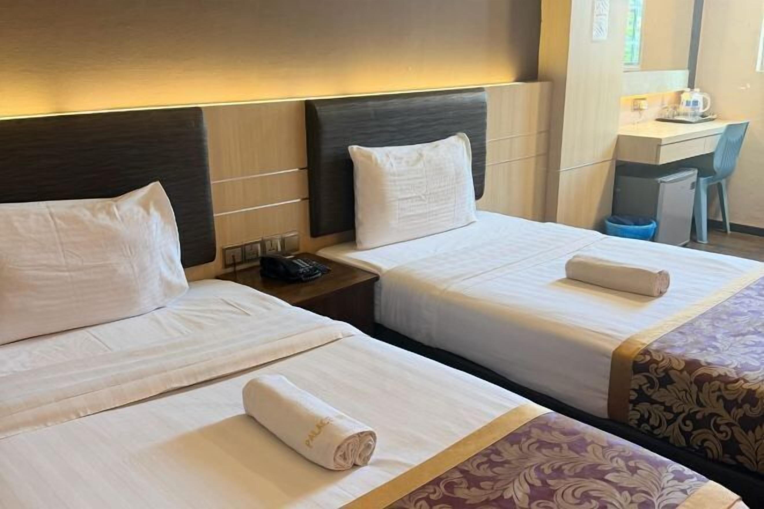 Ein Hotelzimmer mit zwei Betten, einem Schreibtisch und einem Stuhl.