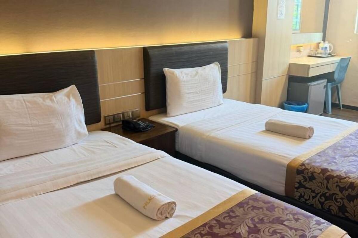 A hotel room with two beds, a desk, and a chair.