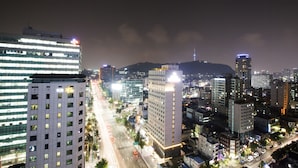 Un hotel moderno de varios pisos, con un letrero llamativo y vista a una concurrida calle urbana de noche.