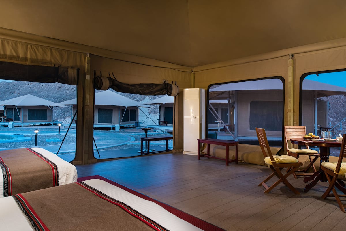 Um quarto com tenda, uma cama, uma mesa de jantar com cadeiras e vista para uma piscina e área externa.