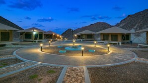 A circular courtyard with outdoor seating and a central fountain, surrounded by tents with windows. - Ras Al Jinz Turtle Reserve (Al Hadd)