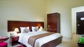 A hotel room with a bed, bedside table, lamp, and a wardrobe.