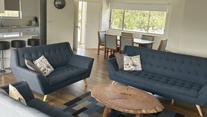 A modern living room with two sofas, a coffee table, and a dining area with a table and chairs. - Portarlington Beach Motel (Portarlington)