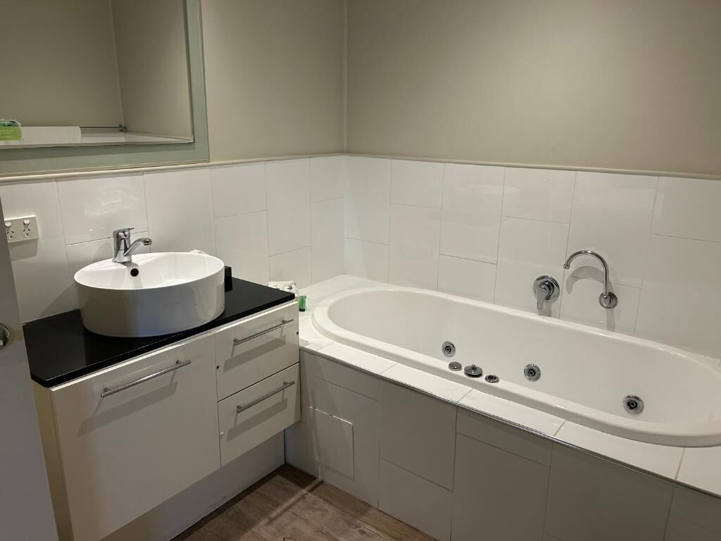 A modern bathroom with a freestanding bathtub, a round sink, and a mirror above the sink.