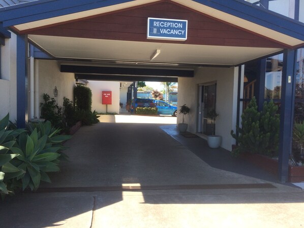 A reception area with a sign indicating vacancy. There is a fire hose reel and a parking sign visible.