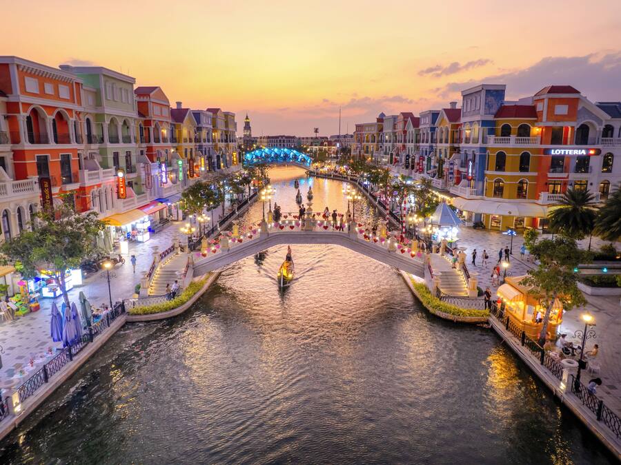 A riverside promenade with a bridge, shops, and a boat service.