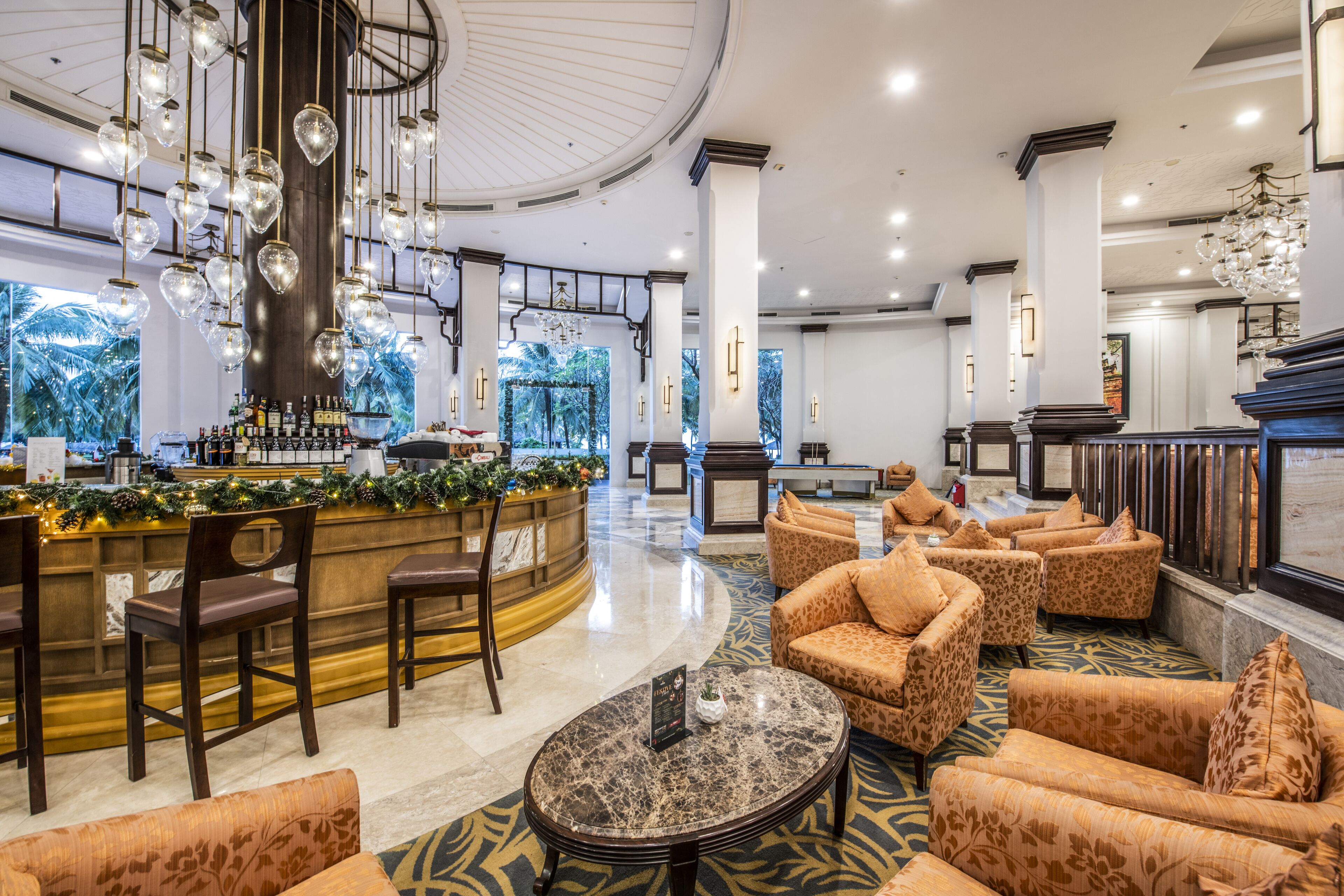 A spacious lobby with a bar area, seating arrangements, and a chandelier.