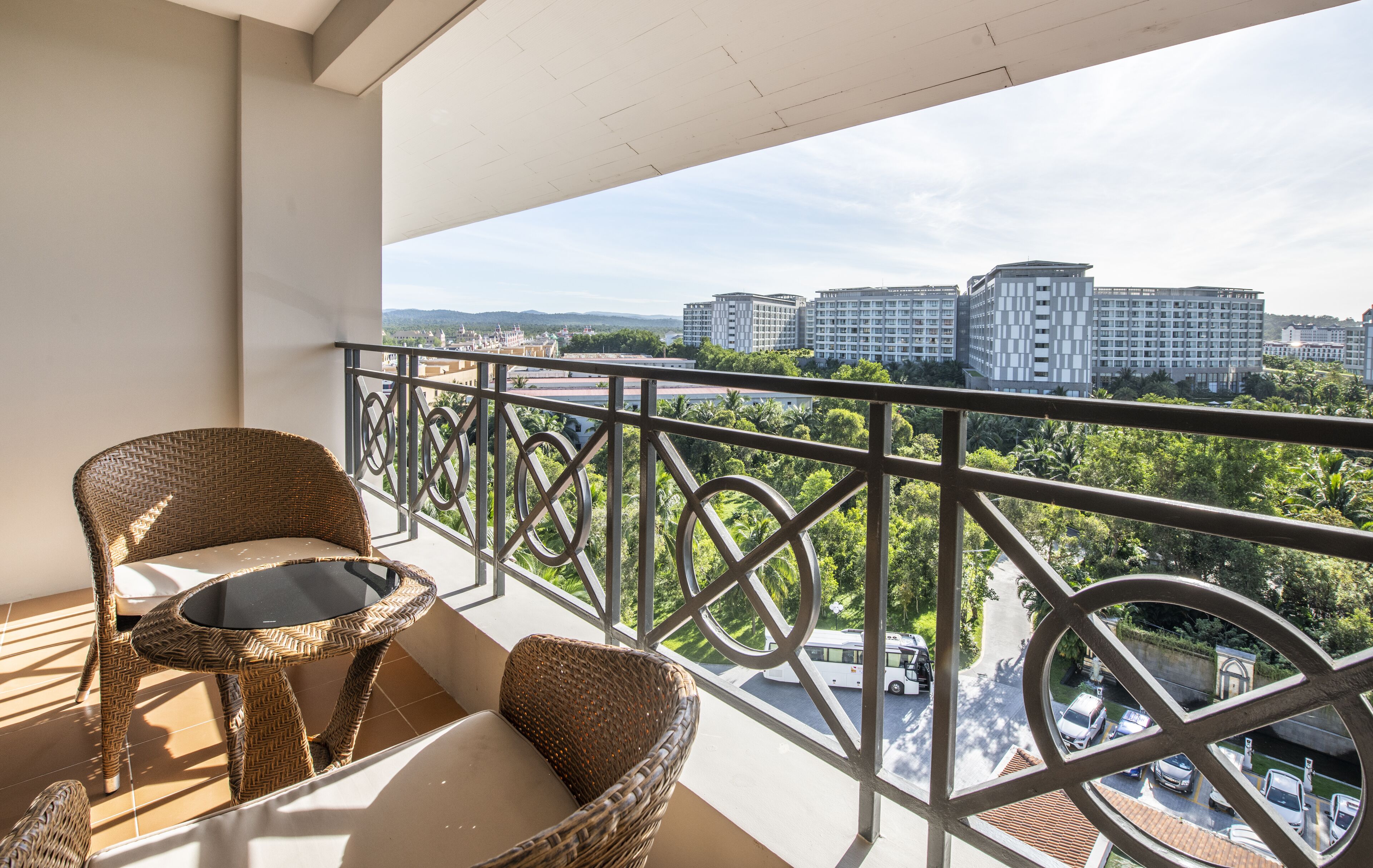 A balcony with wicker furniture and a view of high-rise buildings and greenery.
