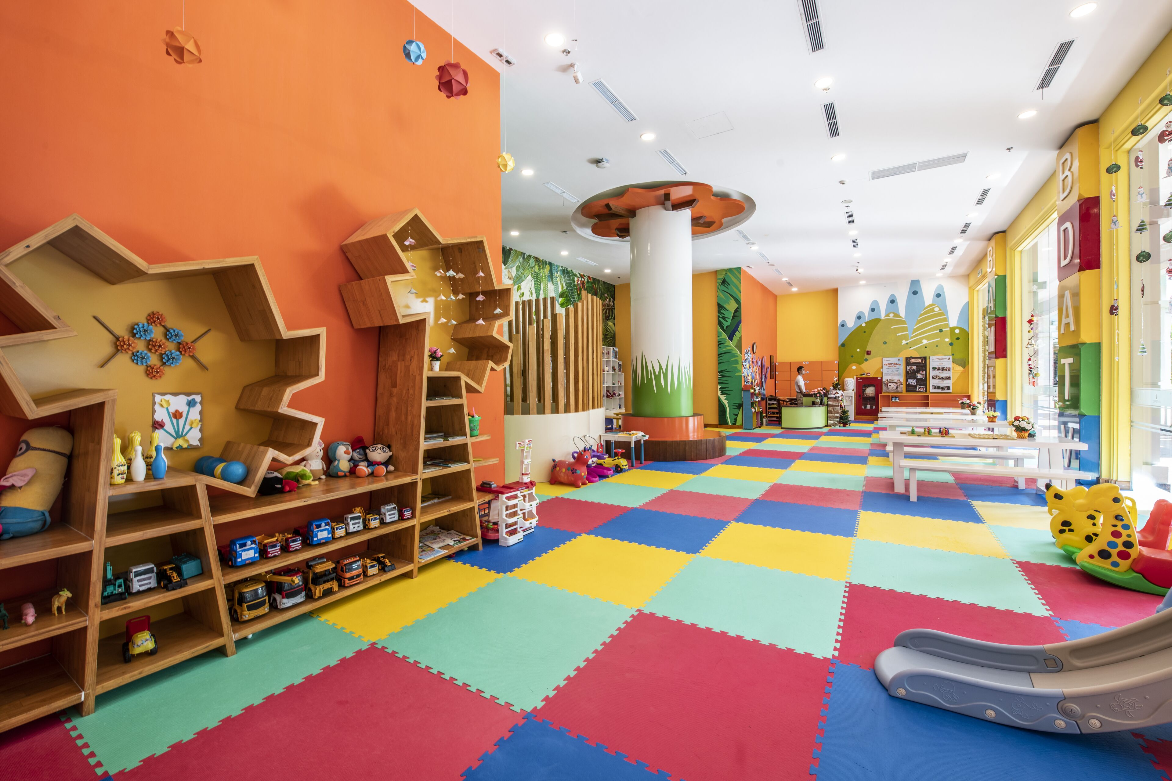 A brightly colored play area with a checkered floor, wooden play structures, and a slide.