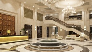 Un lobby espacioso con una recepción, una fuente central y una escalera que conduce a un nivel superior.